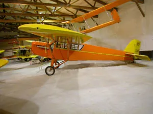 A yellow and orange airplane in an air hangar.