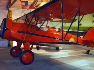 A red airplane is parked in an indoor hangar.