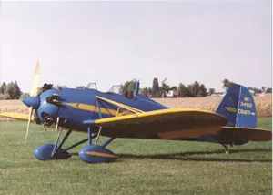 A blue and yellow plane sitting on top of grass.
