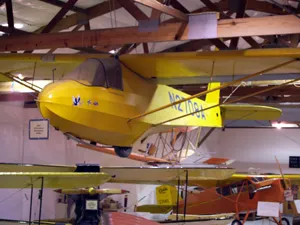 A yellow airplane hanging from the ceiling of an air museum.