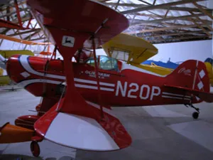 A red and white plane is parked in an airport hangar.