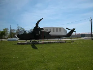 A helicopter sitting in the grass near a building.