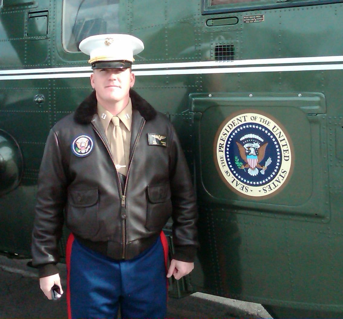 A man in uniform standing next to the president 's train.