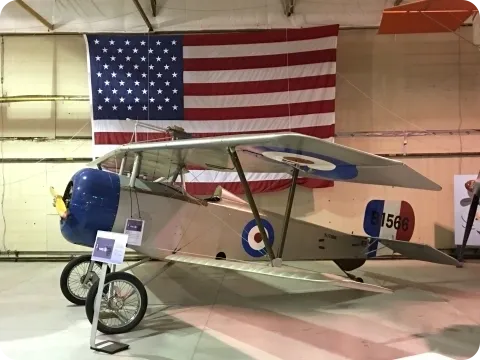 A small plane is on display in front of an american flag.