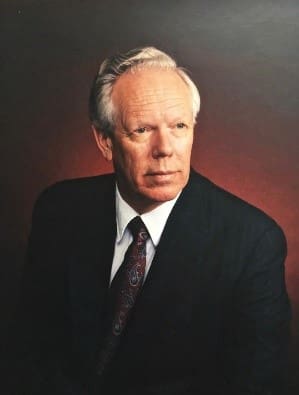 A man in suit and tie sitting down.
