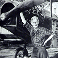A woman standing next to an airplane with her arms raised.