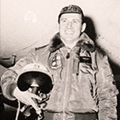 A man in an air force uniform holding a helmet.