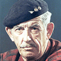 A man wearing an old hat and plaid shirt.