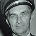 A man in a uniform and hat is smiling.