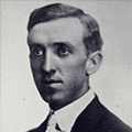 A man in suit and tie with short hair.