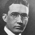 A black and white photo of a man wearing glasses.
