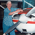 A woman standing next to an airplane in a hangar.