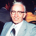 A man in glasses and suit smiling for the camera.