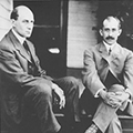 Two men sitting on steps in front of a building.