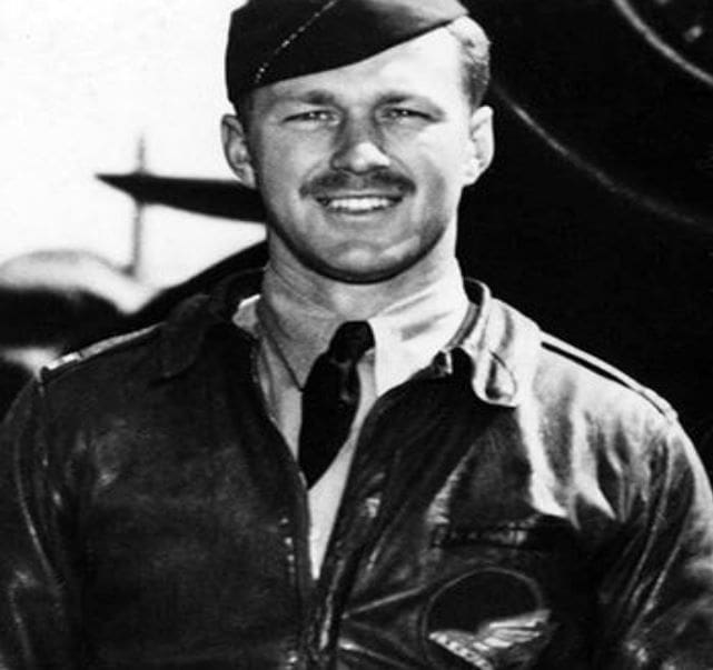 A man in an army uniform standing next to a plane.